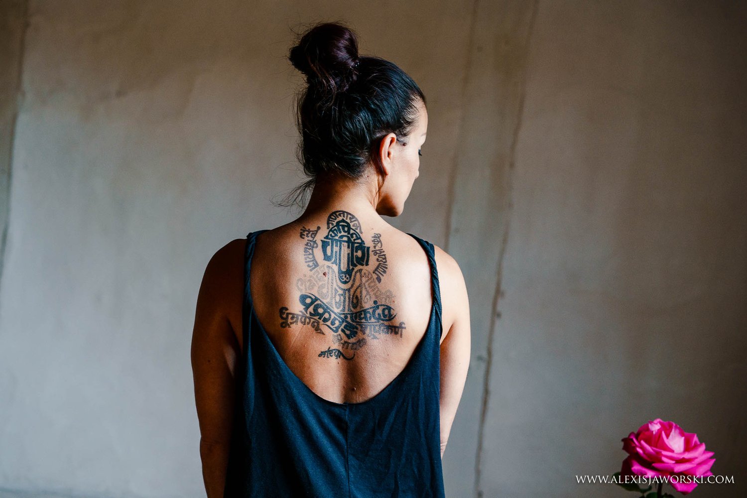Christie photographed from behind in a low-backed vest, hair tied up, turning her head towards the light.