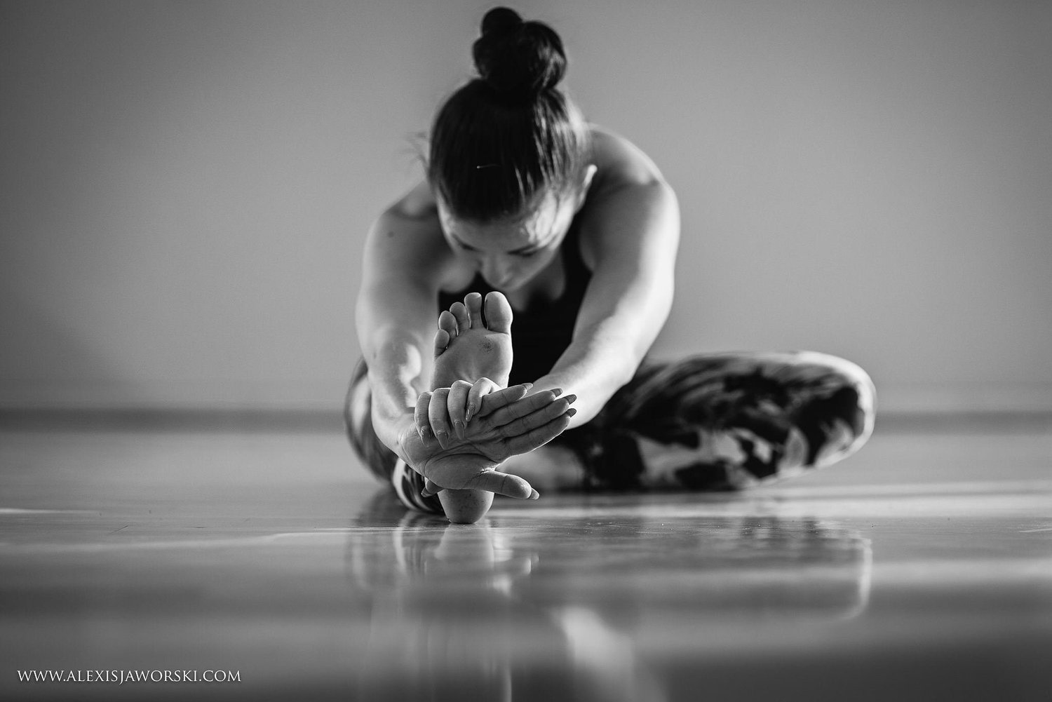 Christie balancing on one leg in the studio, the other leg extended behind her, arms reaching forward.