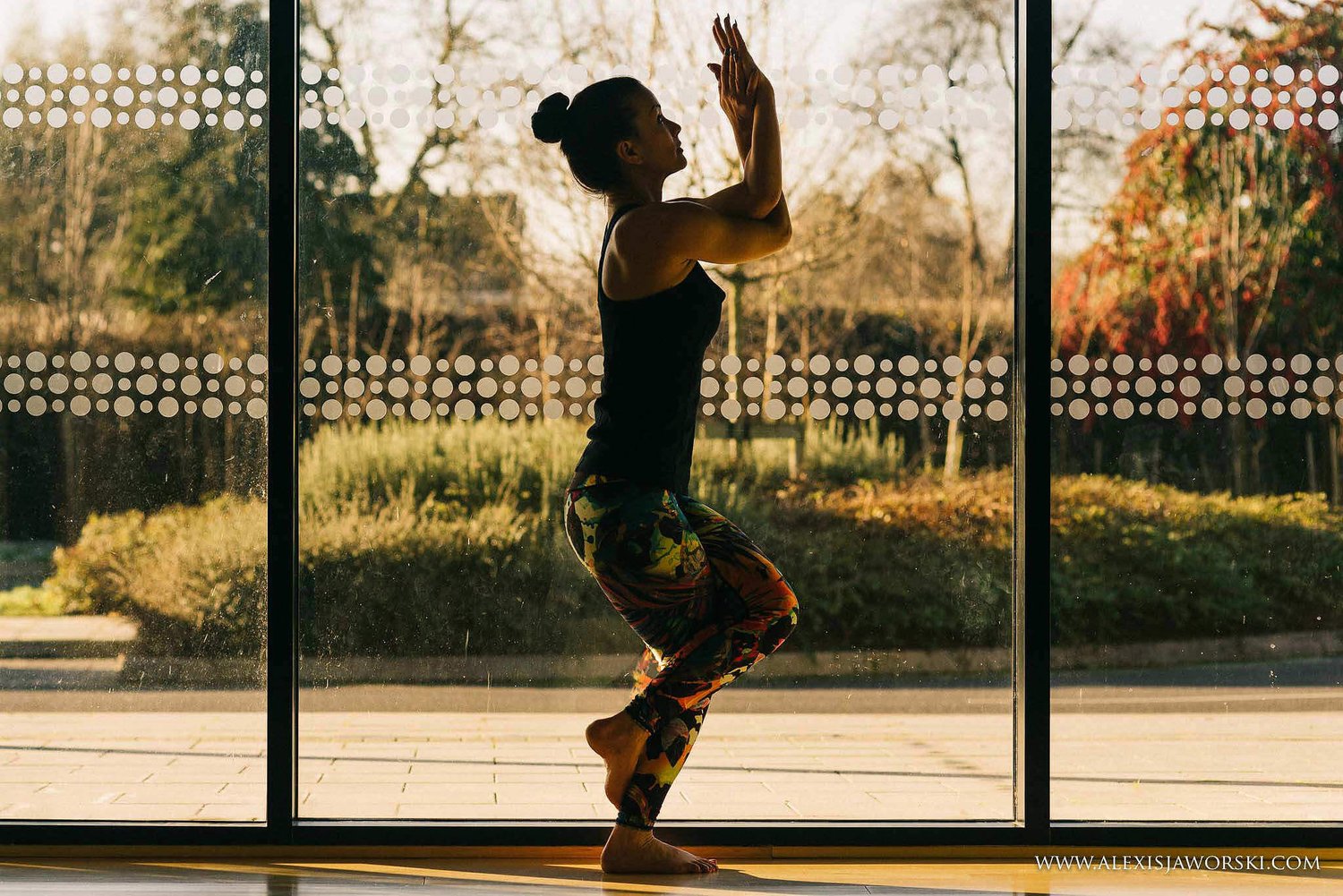 Christie in a standing balance in the studio, framed by the tall windows.